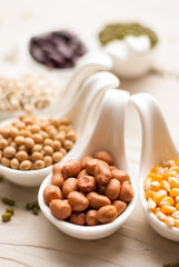Different kinds of bean seeds, lentil, peas in dish on wooden ta