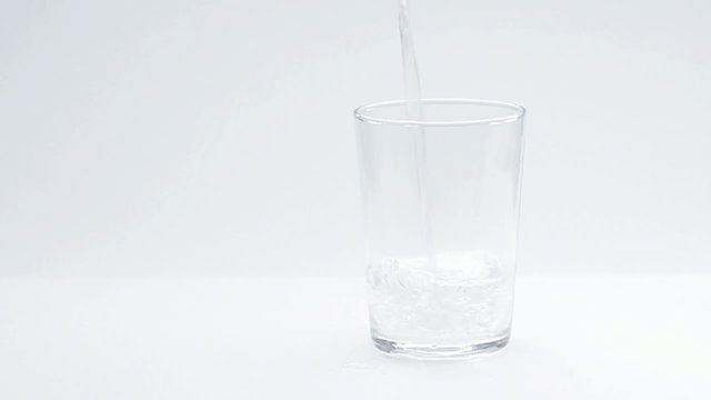 Water pour into a glass, white background