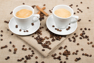 two cups of coffee and coffee beans on the background