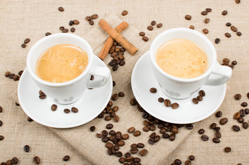 two cups of coffee and coffee beans on the background