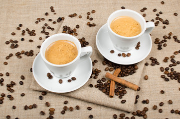 two cups of coffee and coffee beans on the background