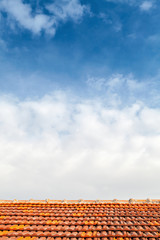 Bbackground with red tile roof and blue cloudy sky