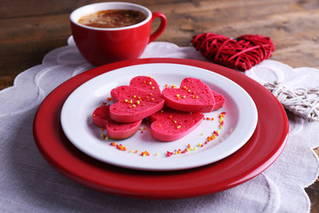 Cookies in form of heart in plate with cup of coffee