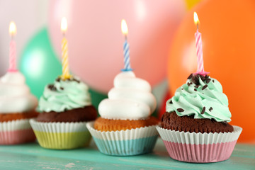 Delicious birthday cupcakes on table on bright background