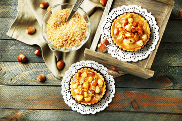 Mini cakes with nuts on napkin on wooden background