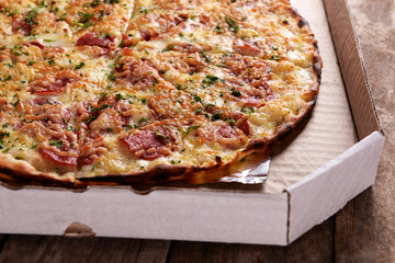 Tasty pizza in box on wooden background