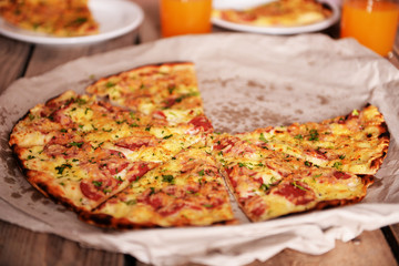 Tasty pizza on paper with glasses of juice on table close up