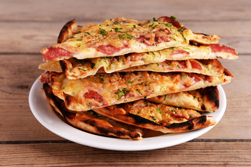 Tasty slices of pizza on plate on wooden table