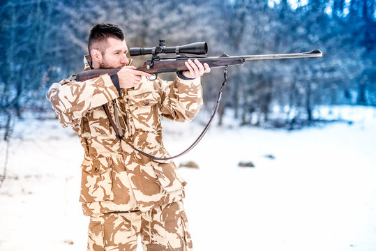 Military man holding a sniper rifle and aiming at enemy