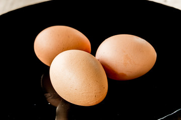 Closeup view of three brown eggs  on the blackdisk