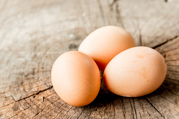 Closeup view of three brown eggs  on the wood