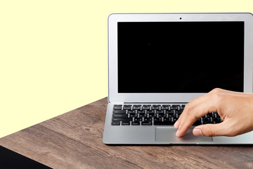 hand using a laptop on wood table, yellow color background