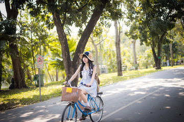 Asian Thai girl in vintage clothing riding a bicycle in summer