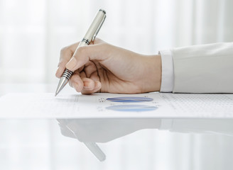 Closeup of woman hand holding pen on graph
