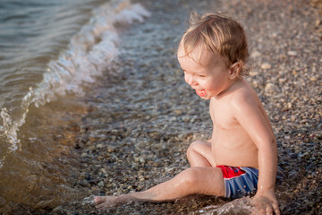 Happy toddler boy playing on the sea