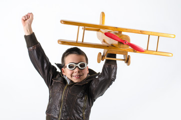 Jubelndes Kind mit Fliegerbrille und Holzflugzeug
