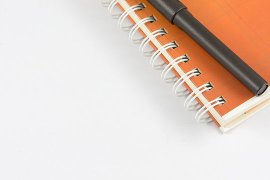 orange note book and black pen