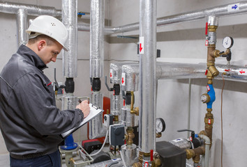 Technician inspecting heating system in boiler room