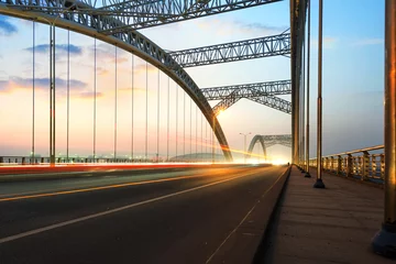 Fototapeten Straße durch die Brücke mit blauem Himmelshintergrund einer Stadt © hxdyl