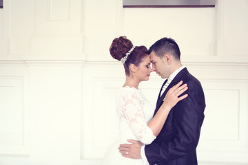 Bride and groom posing in a white palace room