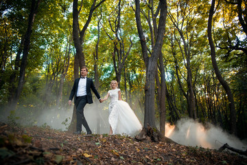 Young wedding couple goes on a picturesque forest. Husband leads