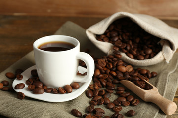 Cup of coffee with beans on rustic wooden background