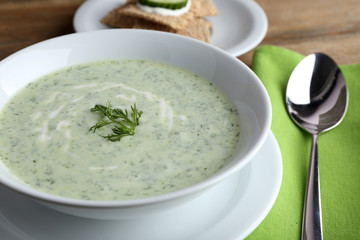 Cucumber soup in bowl on rustic wooden table background