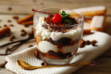Tasty tiramisu dessert in glass, on napkin, on wooden