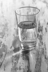 Glass of clean mineral water on old color wooden background