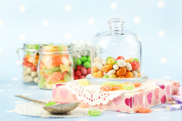 Multicolor candies in glass jars on colorful background