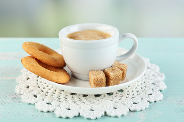 Cup of coffee and tasty cookie on color wooden background