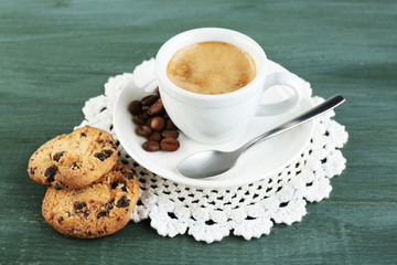 Cup of coffee and tasty cookie on color wooden background