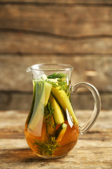 Glass ewer with fresh organic cucumber water on wooden table