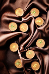 Tasty chocolate candies on satin cloth, close up