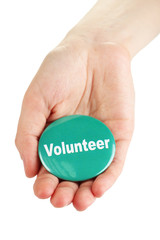 Round volunteer button in hand isolated on white