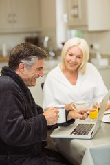 Mature couple having breakfast together man using laptop
