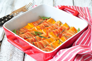 the pieces of pumpkin are baked in a bacon with rosemary
