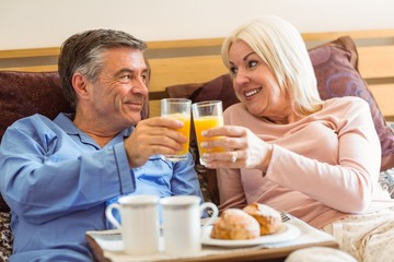 Happy mature couple having breakfast in bed