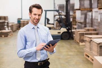 Manager using digital tablet in warehouse