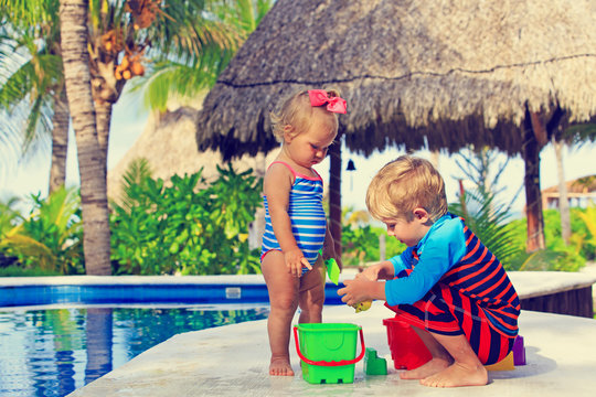 little boy and toddler girl playing in swimming pool