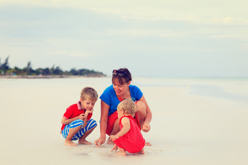 mother with kids playing on beach