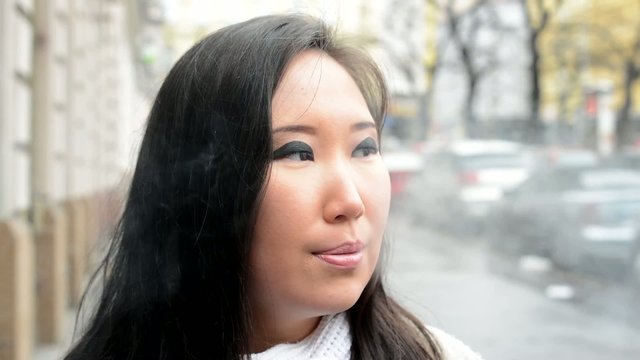 young attractive asian woman smokes - street - closeup