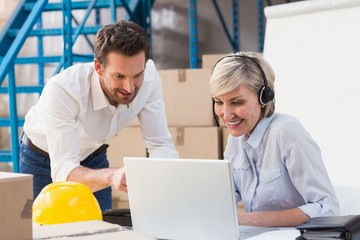 Warehouse managers using laptop and wearing headset