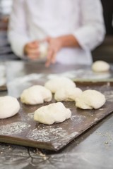 Fototapeta na wymiar Baker kneading uncooked dough on worktop