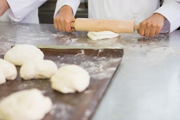 Baker kneading dough with rolling pin