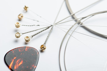Electric guitar strings with mediator on white surface