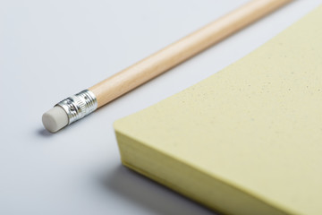 Yellow notepad with pencil on white surface