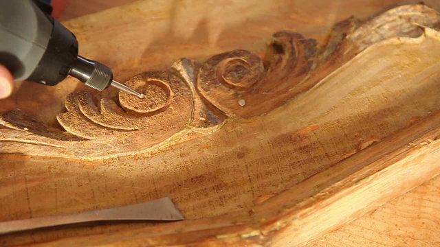 Close up of carpenter carving wood with engraver tool.