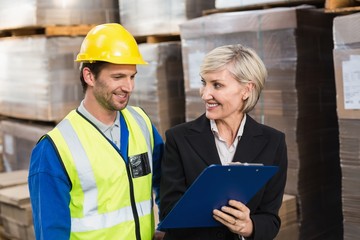 Warehouse manager showing clipboard to her colleague