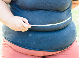 Fat mature woman measuring her belly with measurement tape